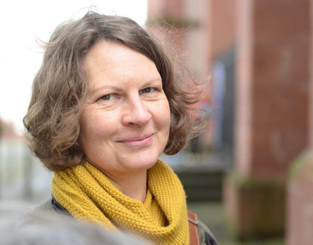 Nena mit leicht lockigen Haaren und gelbem Schal, Kursleiterin für den Yoga-Kurs "Bewegen - entspannen - sein"